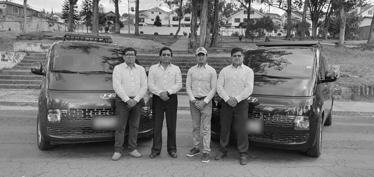 Cuatro conductores de C.I.M con camisa blanca, de pie entre dos vans Hyundai Staria de la flota