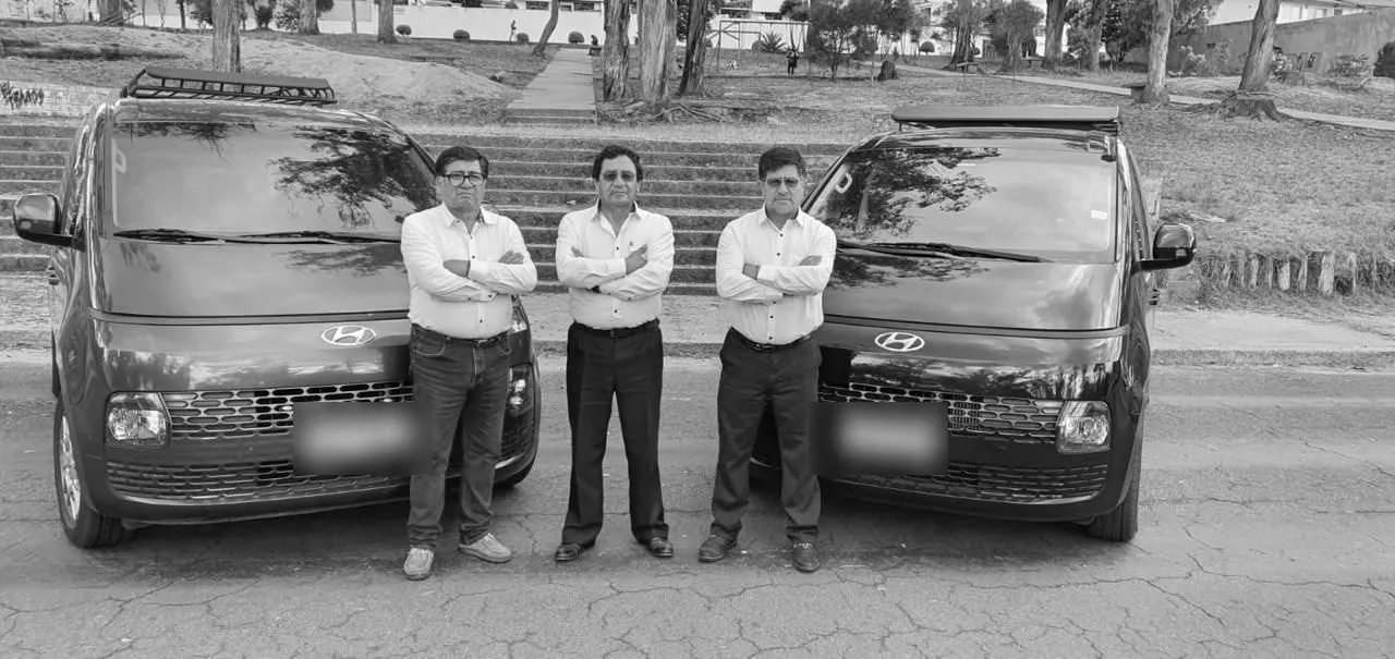 Tres conductores de C.I.M con camisa blanca junto a dos vans Hyundai Staria de la flota
