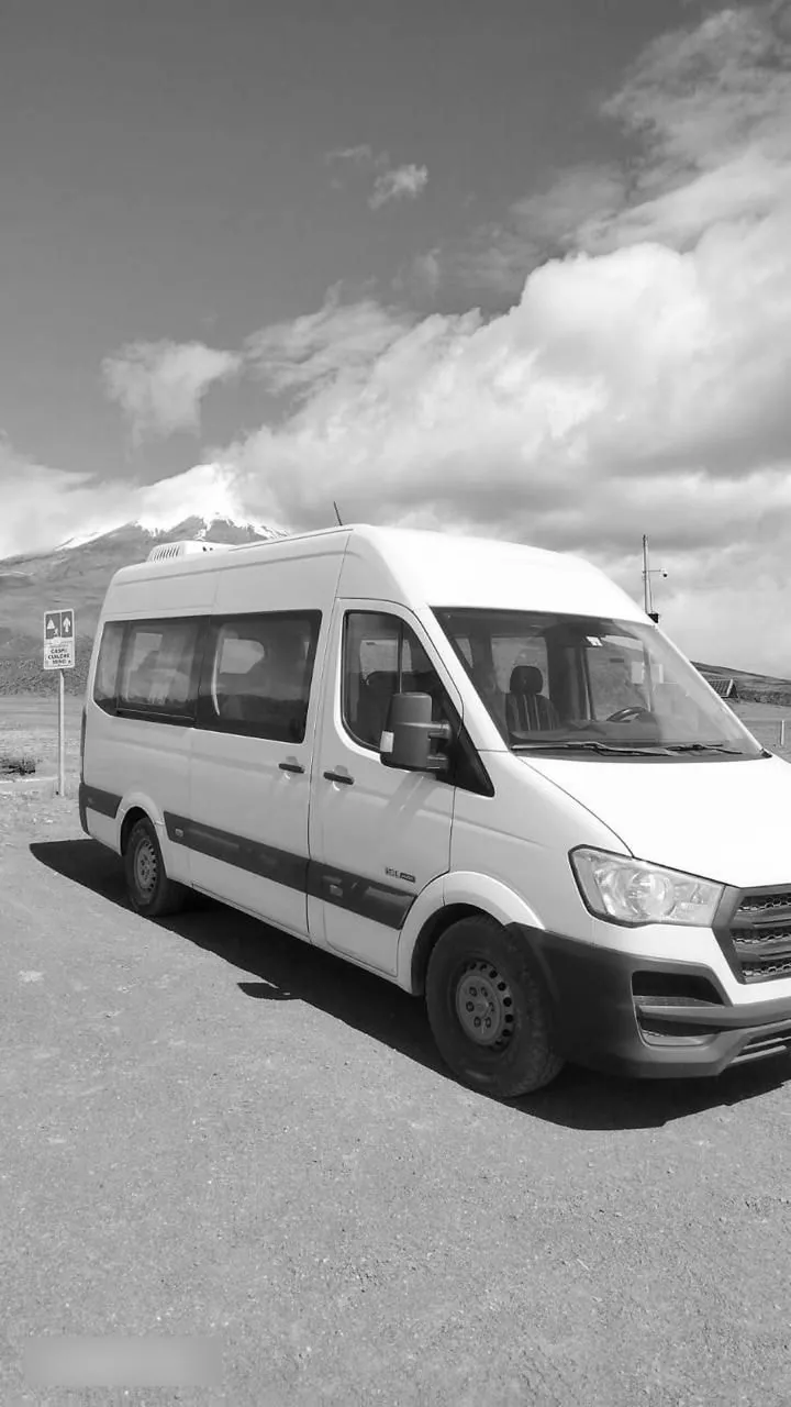 Van blanca de pasajeros de C.I.M en carretera, con montañas al fondo